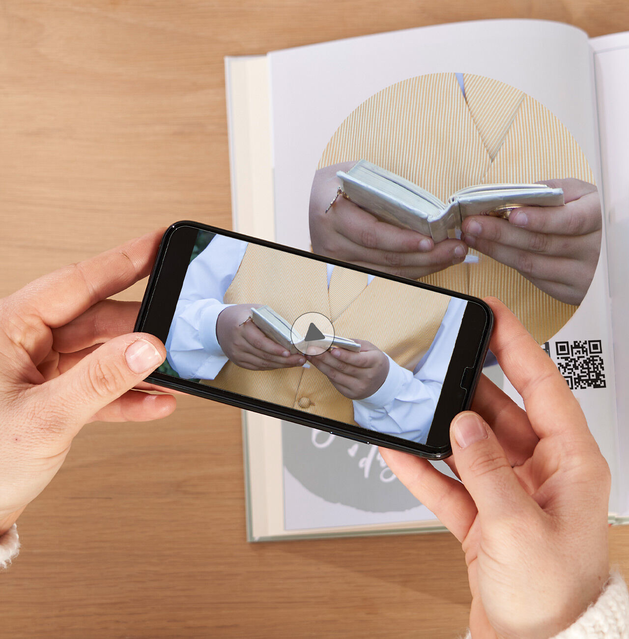 Una persona graba un álbum con un smartphone. Ambos están sobre una mesa.