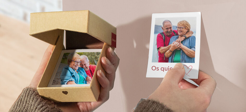 Una persona sostiene una pequeña caja de regalo con una foto dentro, y otra foto en la mano con dos personas juntas.