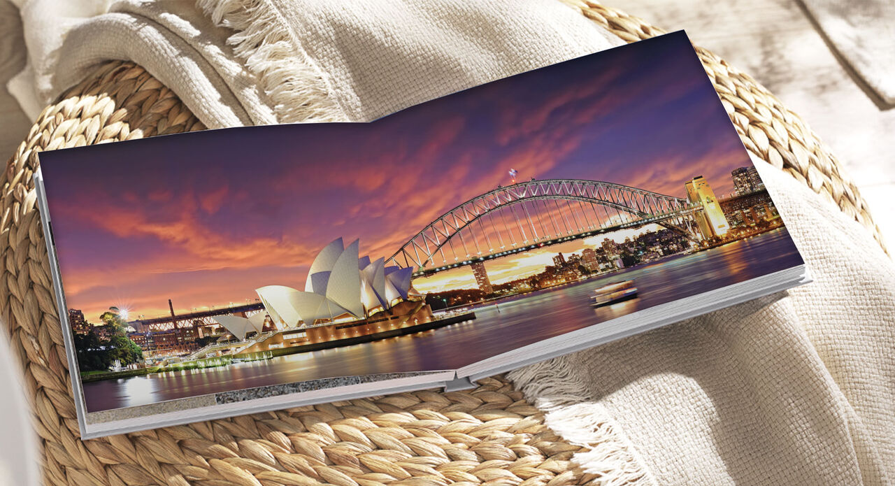 Un álbum de fotos abierto muestra la Ópera de Sydney y el Puente de la Bahía al atardecer.