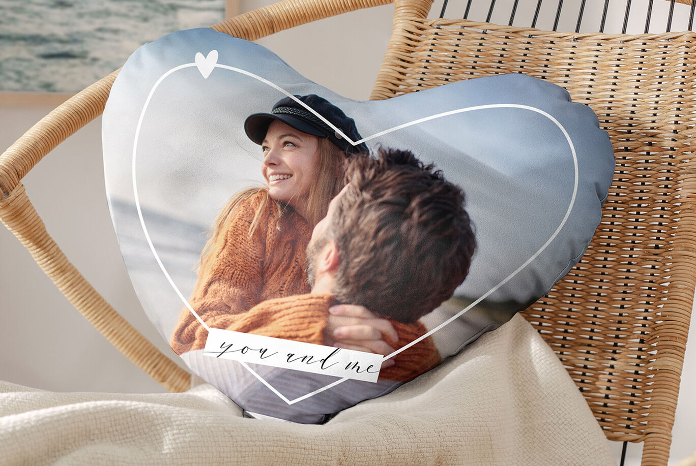 Cojín en forma de corazón con una pareja feliz en la playa.