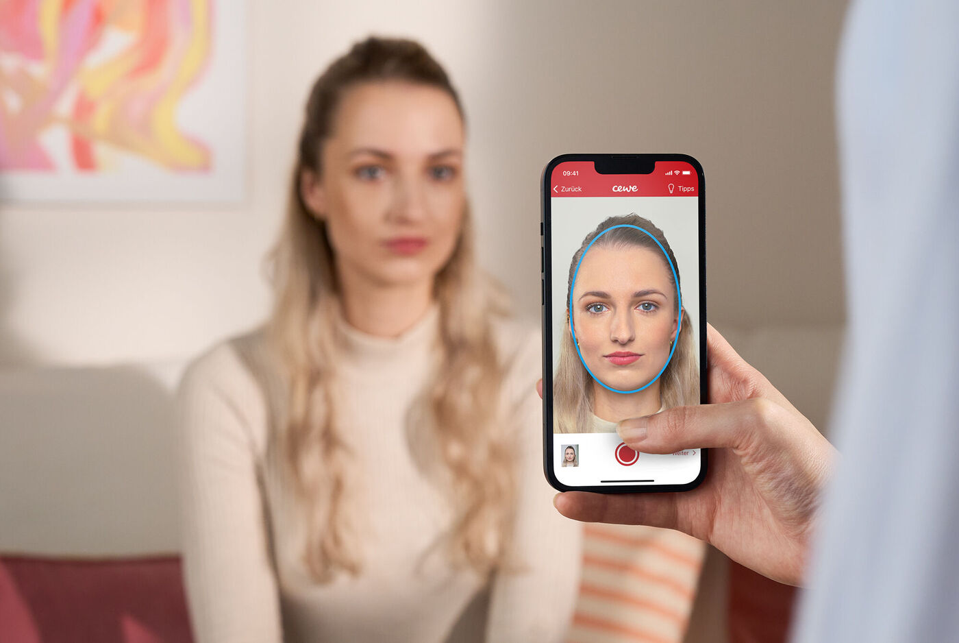 Persona sosteniendo un teléfono móvil mientras toma una fotografía a otra persona sentada en un entorno interior