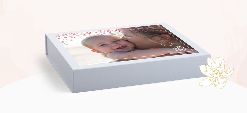 Un niño feliz es besado por una persona cariñosa, con un diseño de caja de regalo y un patrón floreado.