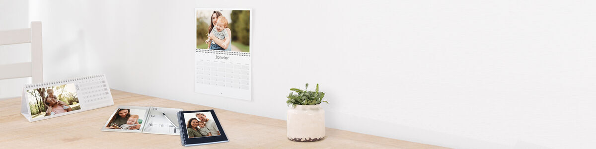 Una mesa con un calendario y varias fotos en un hermoso arreglo.