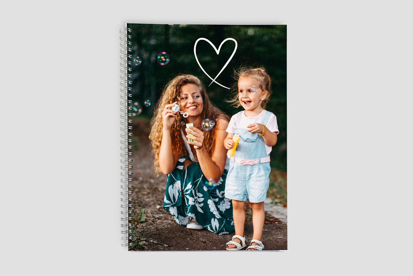 Una madre sopla burbujas con su hija en la naturaleza. Ambas disfrutan jugar.