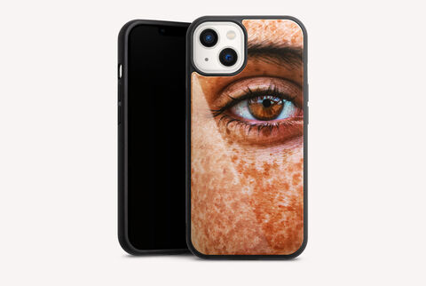 Close-up de un rostro con pecas de verano y un ojo marrón vivo en un teléfono móvil