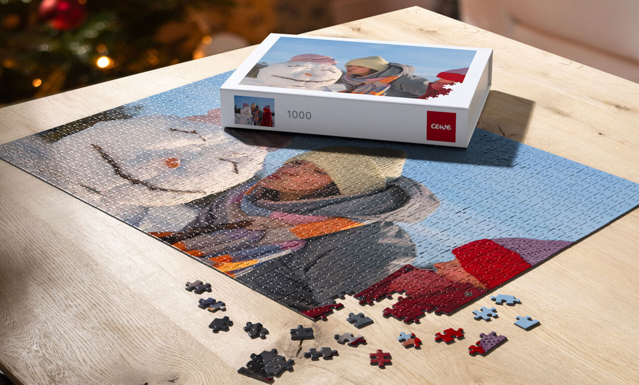 Puzzle personalizado con foto de vacaciones de invierno y muñeco de nieve, a medio armar con piezas sueltas y su caja de regalo