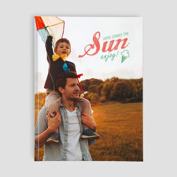 Un niño está sobre los hombros de un adulto sosteniendo un colorido dragón. Sonríen disfrutando del día soleado.