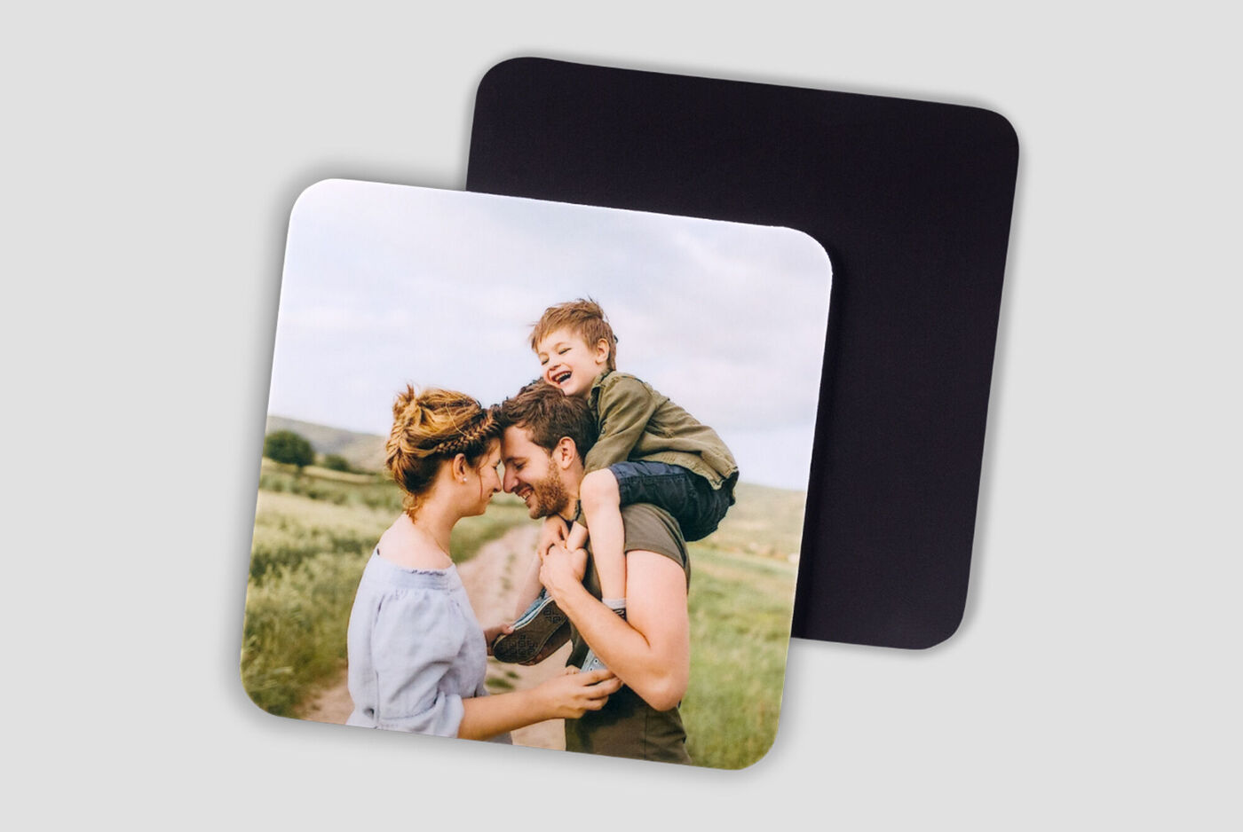 Una familia disfruta de un bello momento al aire libre. Un niño sonríe en la espalda de un padre. Fondo de campos verdes.