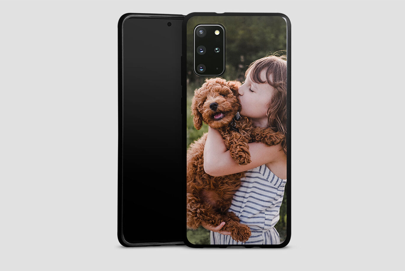 Niña sostiene un perro marrón rizado en brazos y sonríe feliz.