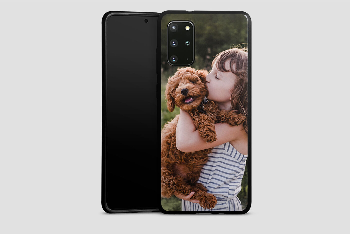 Niña sostiene un perro marrón rizado en brazos y sonríe feliz.