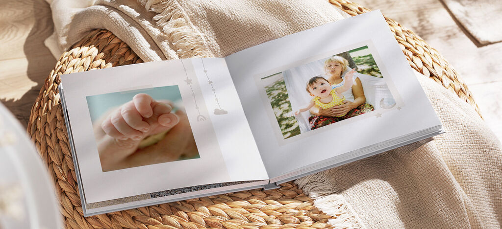 Libro de fotos abierto con fotos de bebés y una madre con su hijo sobre una manta.