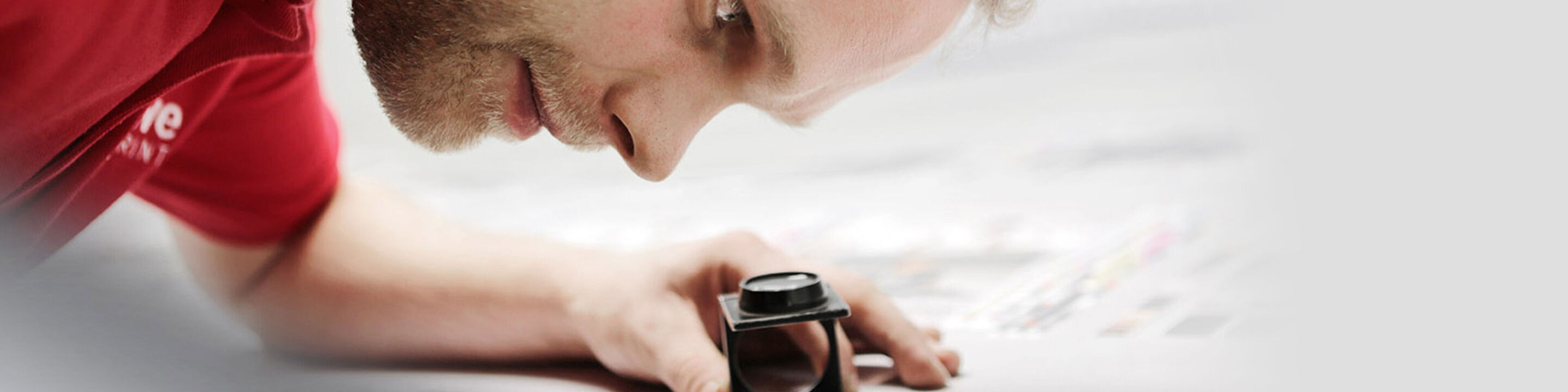 Un empleado de CEWE verifica cuidadosamente la impresión de una foto con una lupa