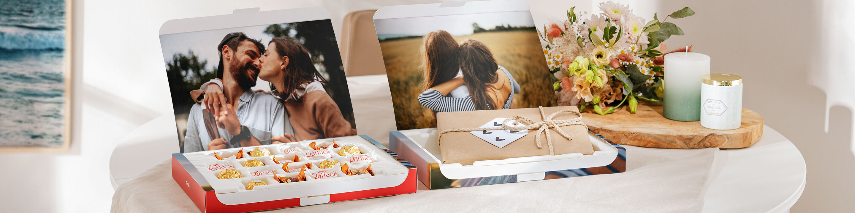 Dos CEWE Fotobooks sobre una mesa con fotos entrañables. Uno muestra una pareja abrazándose, el otro un paisaje romántico.