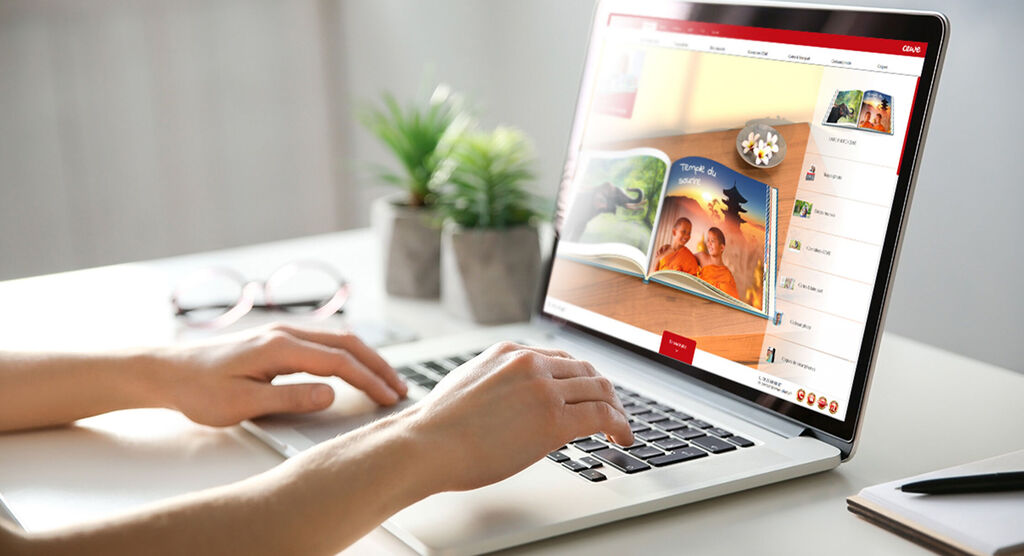 Persona trabaja en una laptop, mostrando un libro de fotos CEWE en la pantalla.