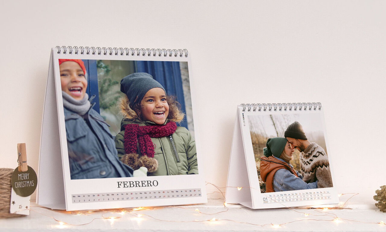 Dos calendarios de fotos personalizados en una mesa, uno con una pareja en bufandas cálidas, el otro con un abrazo amoroso