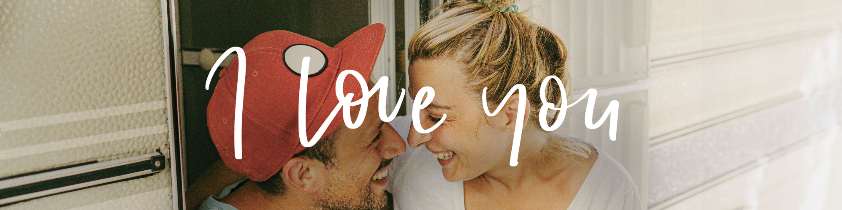 Joven con gorro rojo besa a otra persona en la mejilla, fondo de pared clara