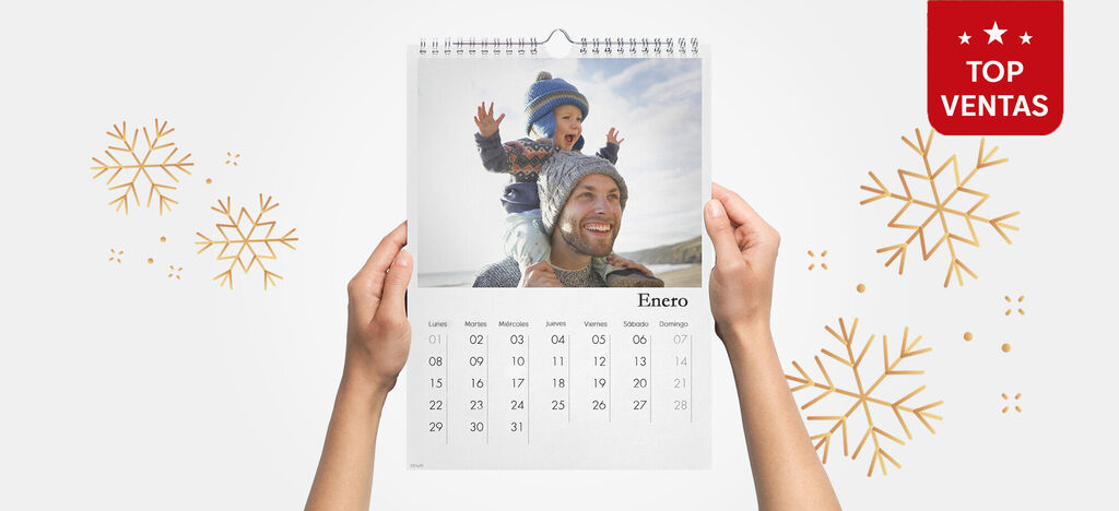 Una mano sostiene un calendario con un niño feliz que ríe y disfruta de la nieve.