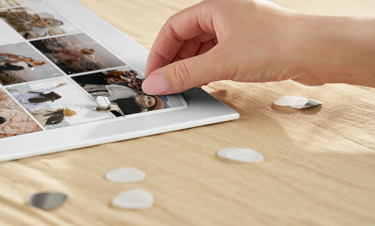 Mano colocando elementos gráficos en un álbum de fotos.