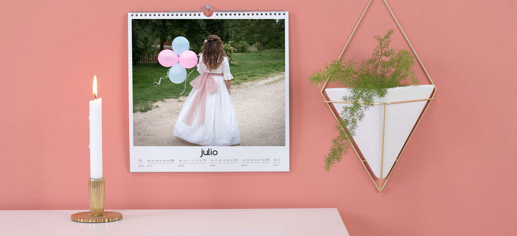 Un calendario con un niño feliz en vestido blanco, jugando con globos de colores.