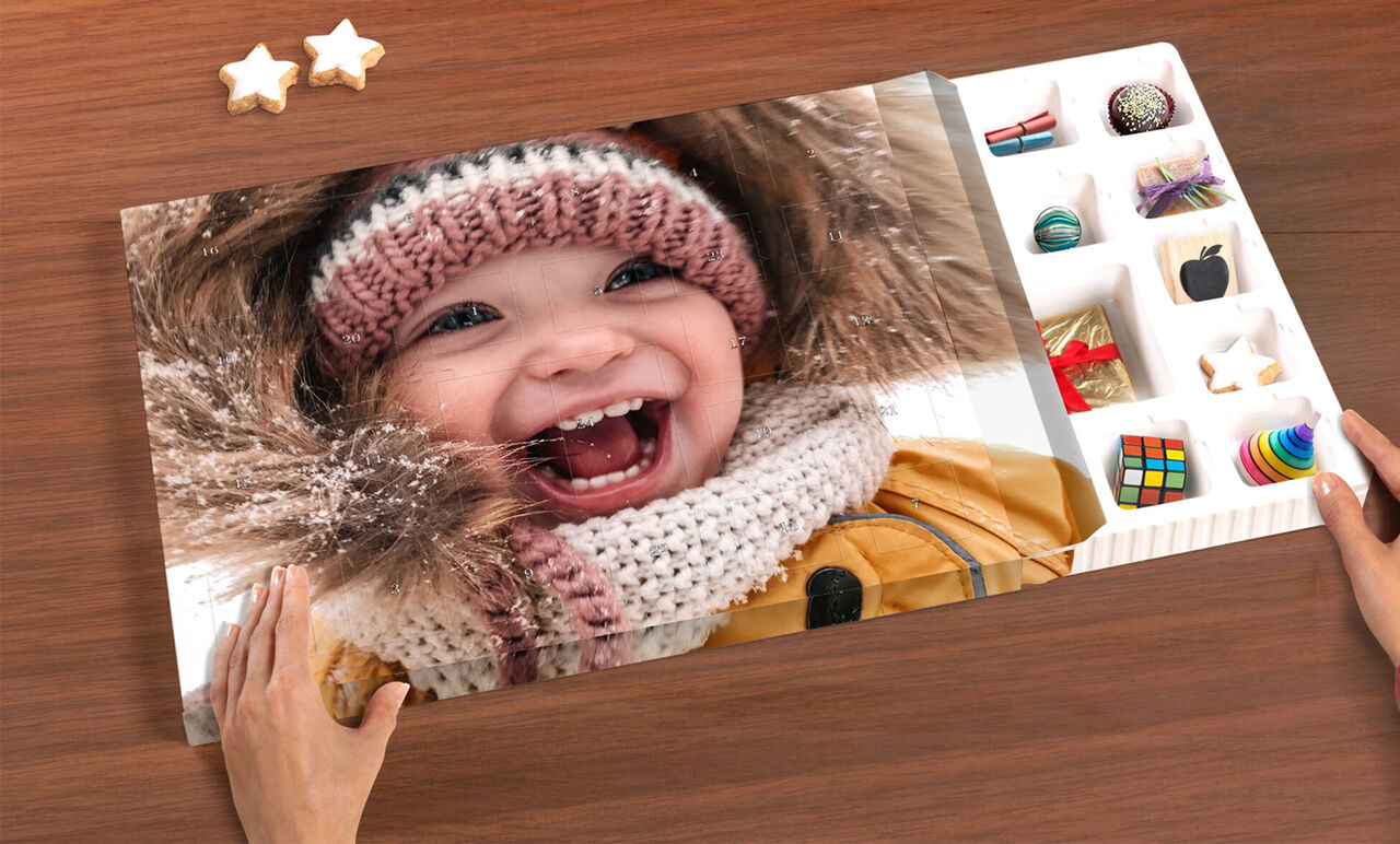 Un álbum de fotos abierto con instantáneas personales y recuerdos bellamente diseñados. Manos sosteniendo el libro sobre una superficie de madera.