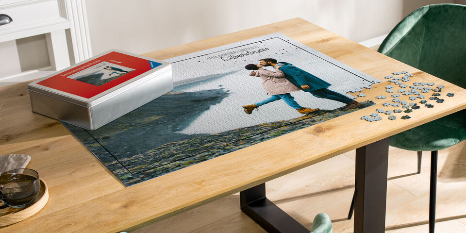 Una pareja escala una roca y disfruta del tiempo juntos, con un rompecabezas y una caja personalizada sobre la mesa.