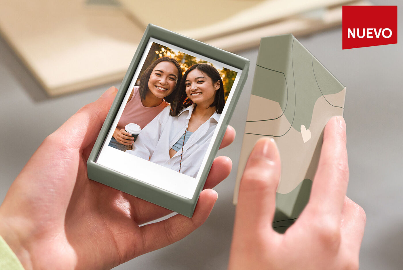 Manos sostienen una caja con una foto en el interior de alguien con una taza.