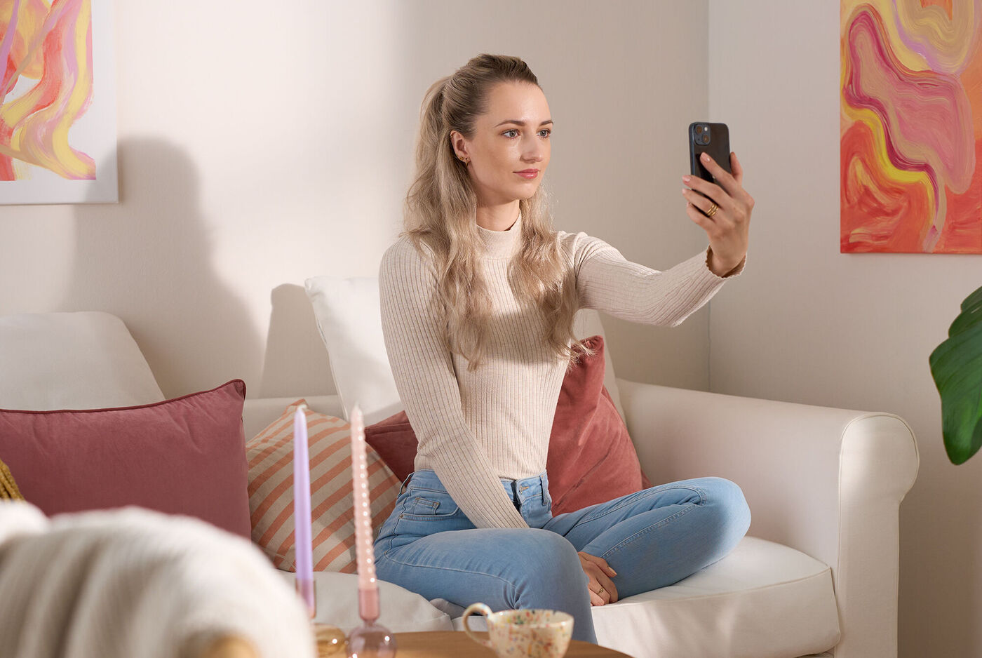 Persona sentada en un sofá tomando una fotografía con su teléfono móvil en un entorno hogareño