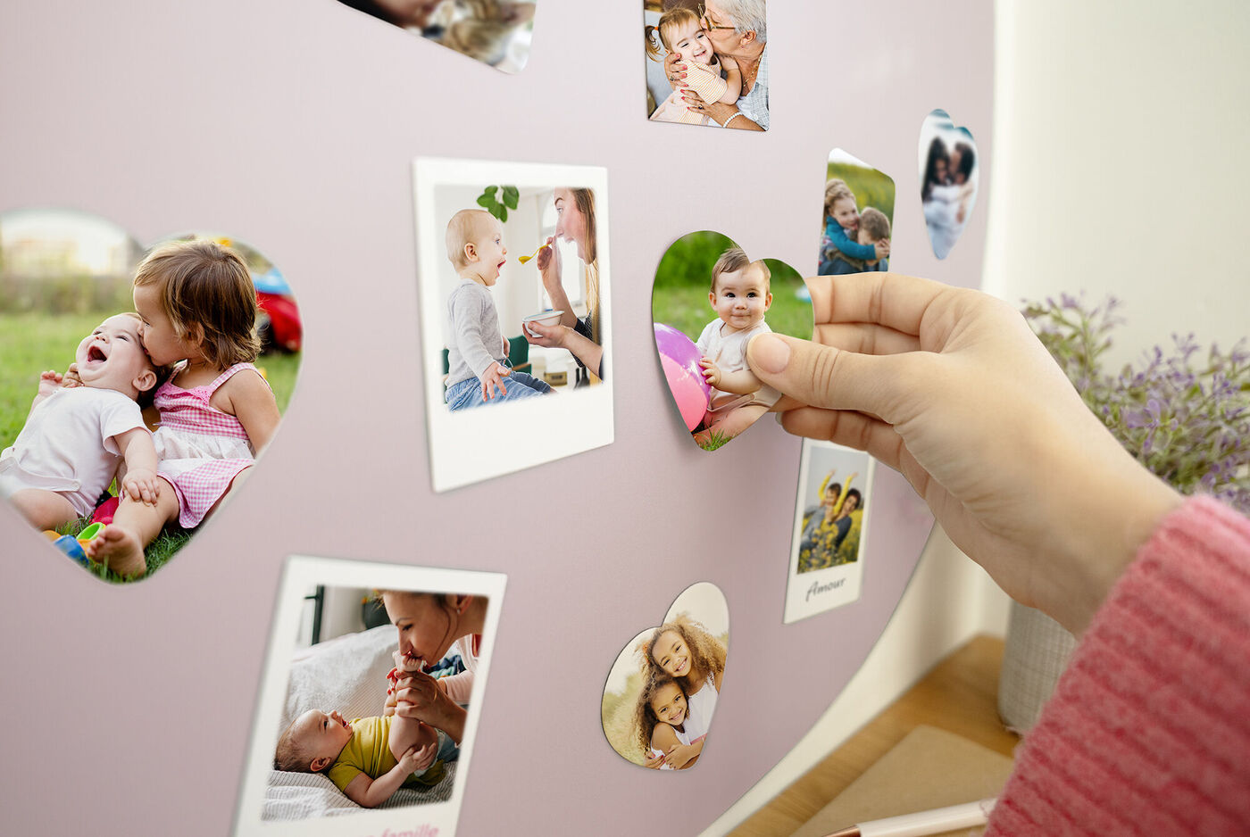 Una persona cuelga fotos en forma de corazón en una pared con lavanda.
