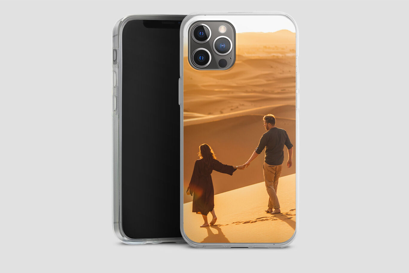 Una pareja pasea de la mano en una duna de arena al atardecer.