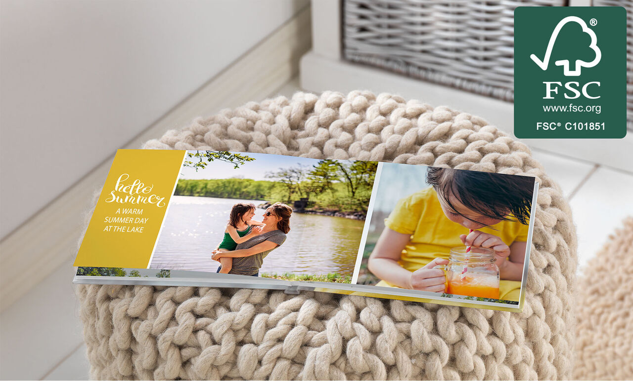 Una familia disfruta de un cálido día de verano junto al lago con un álbum CEWE en un taburete.