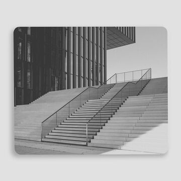 Escalera moderna frente a un edificio de vidrio con líneas claras.