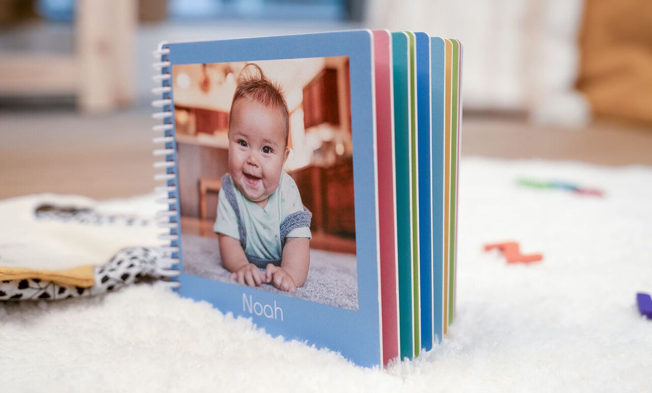 álbum de fotos de un bebé llamado Noah sobre una alfombra.
