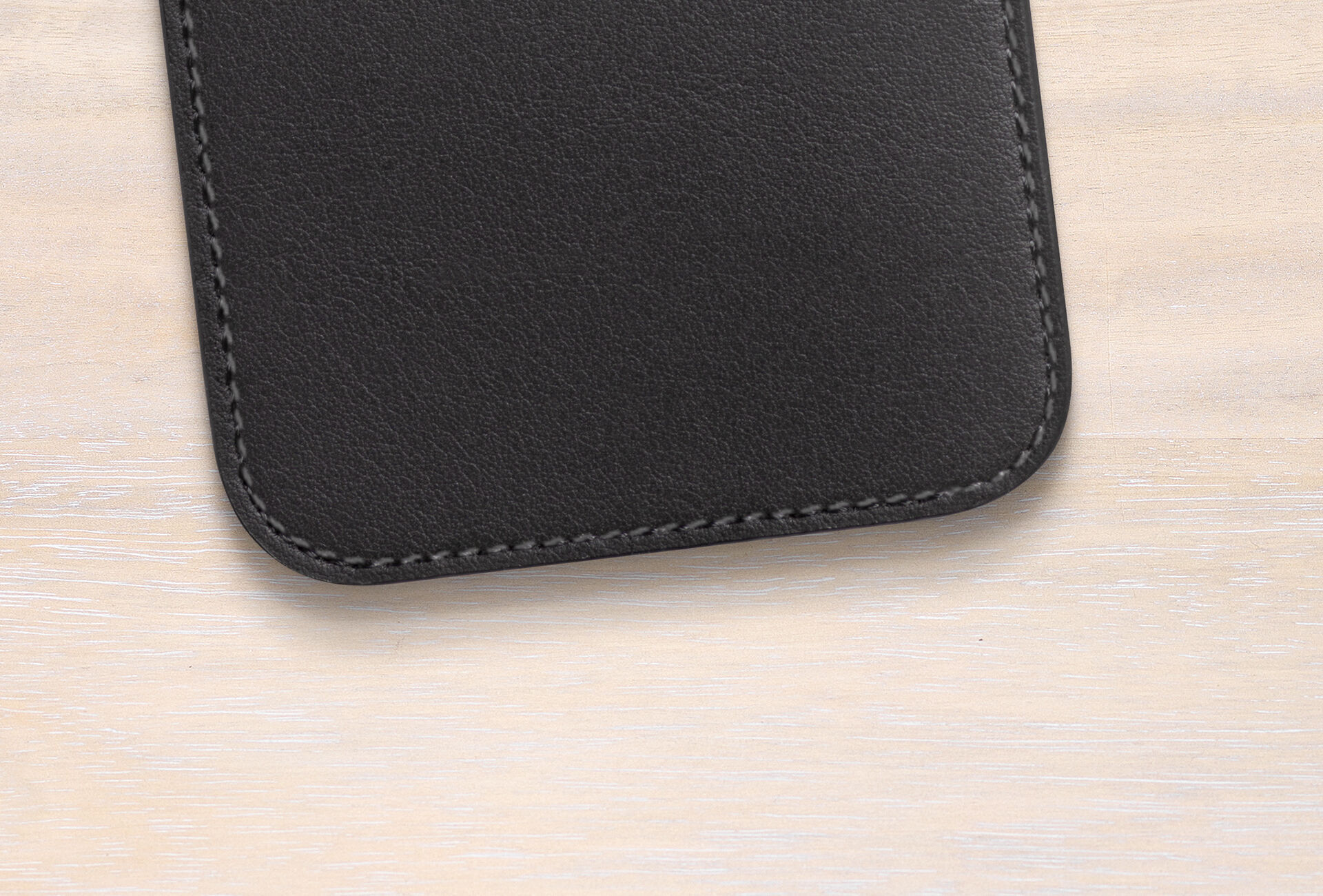 Funda de cuero negra premium sobre fondo de madera clara.