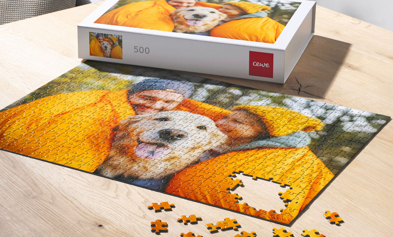 Puzzle fotográfico personalizado de 500 piezas con caja de presentación. Muestra una foto familiar con mascota y piezas sueltas sobre.