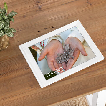 Un fotolibro sobre una mesa clara. Las manos de una persona sostienen algunas piedras brillantes. El título del fotolibro es "Mario".