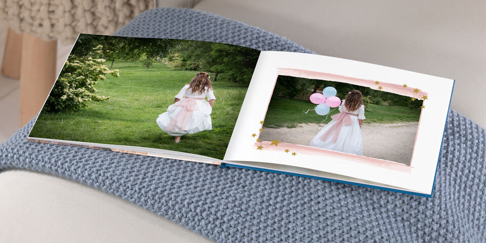 Una niña en vestido blanco alegremente corre con tres globos hacia un álbum en un banco.