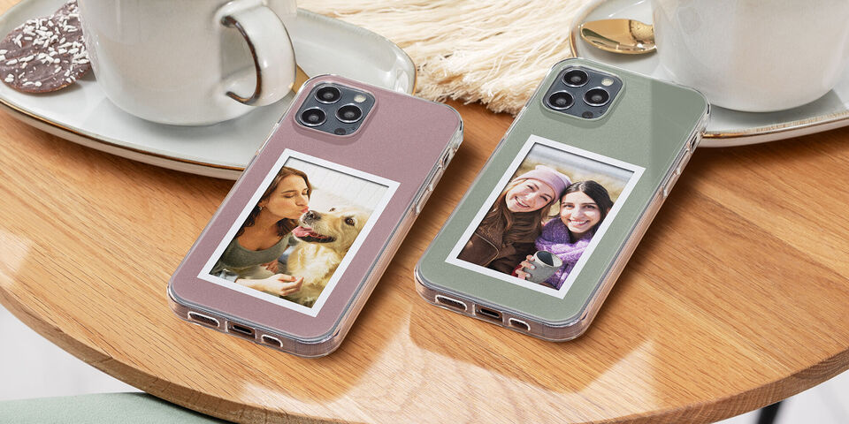 Dos fundas de teléfono con fotos personales sobre una mesa de madera junto a tazas.