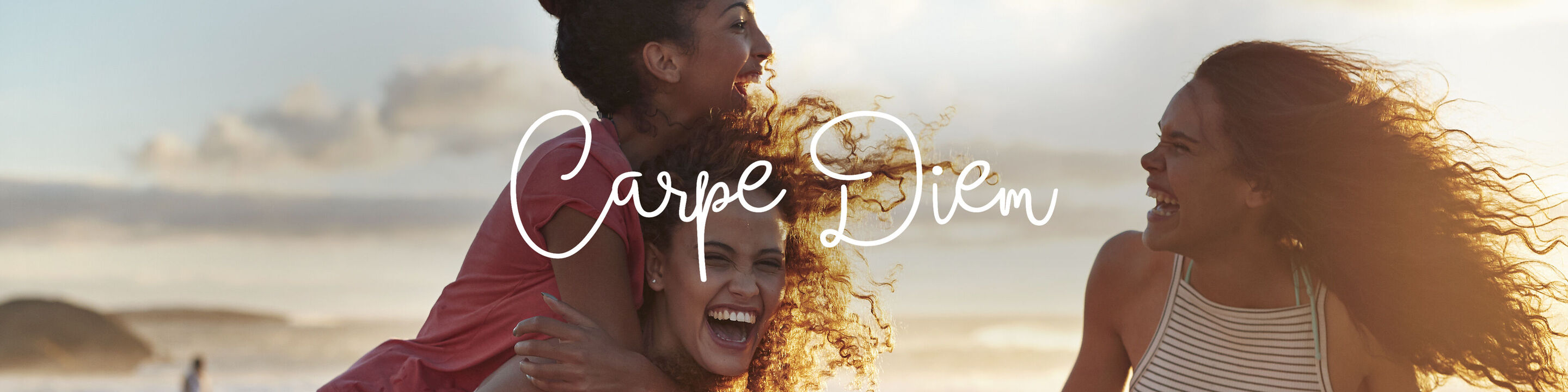 Dos mujeres se abrazan en la playa con un atardecer de fondo