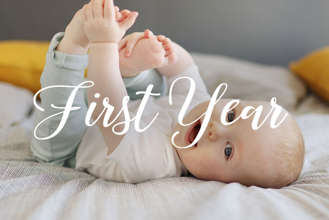 Un bebé está acostado de espaldas jugando con sus piernas en una cama. Cojines amarillos están de fondo.