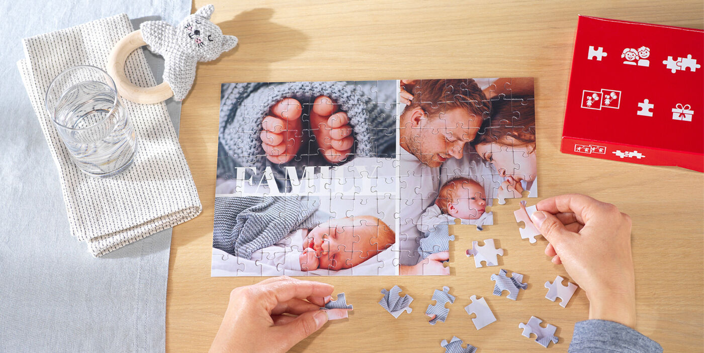 Una persona con resolviendo un puzzle personalizado CEWE con una foto de su familia casi totalmente acabado.