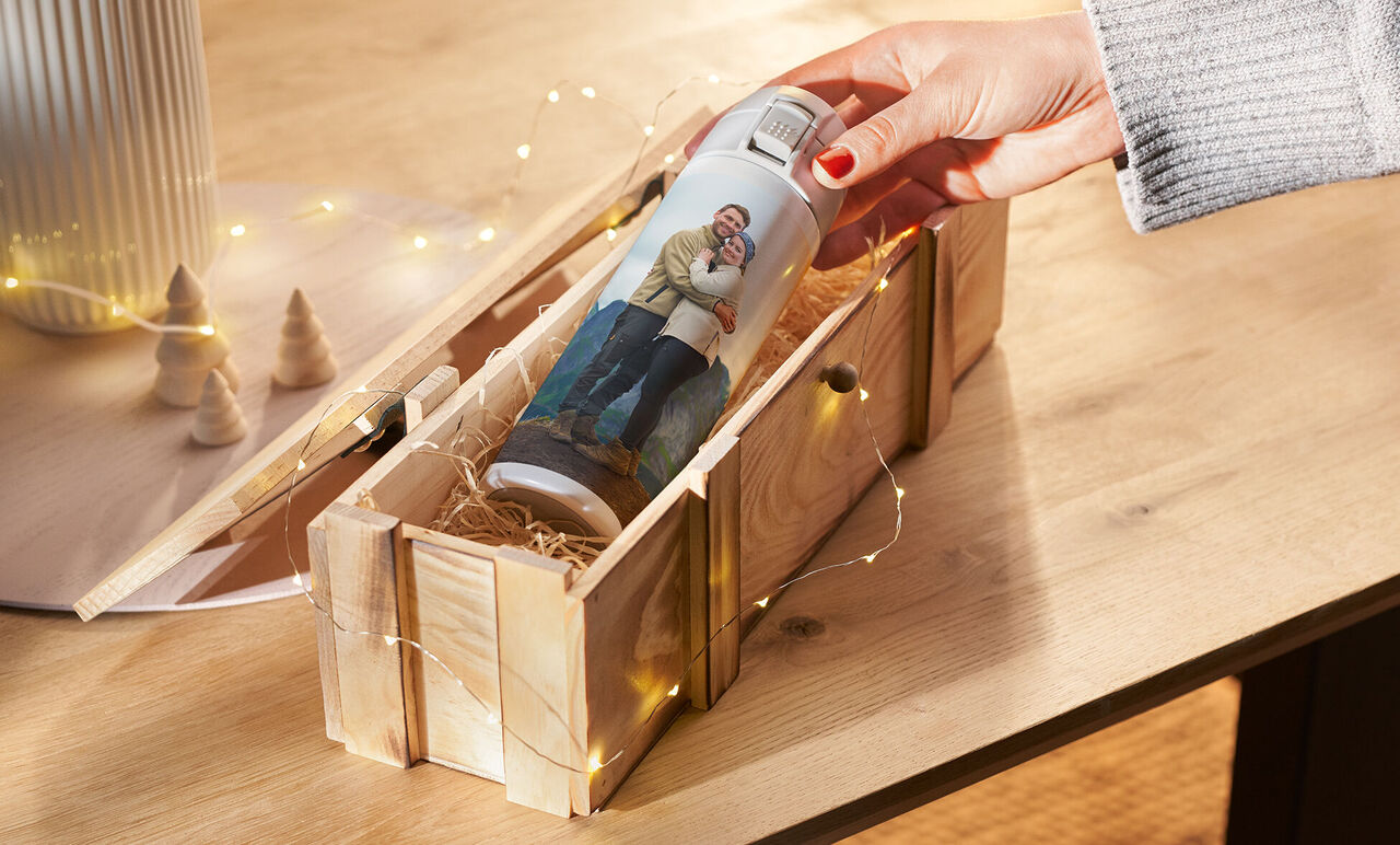 Una persona saca una botella personalizada de una caja de madera decorada.
