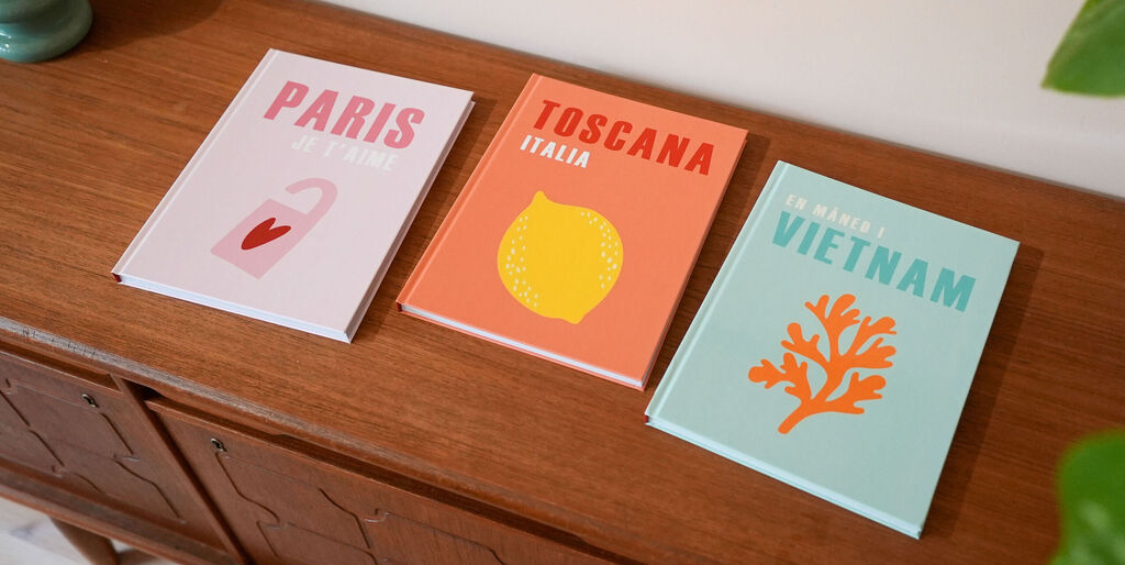 Tres álbumes de fotos de la Colección Mundo con diseños coloridos, dedicados a París, Toscana y Vietnam.