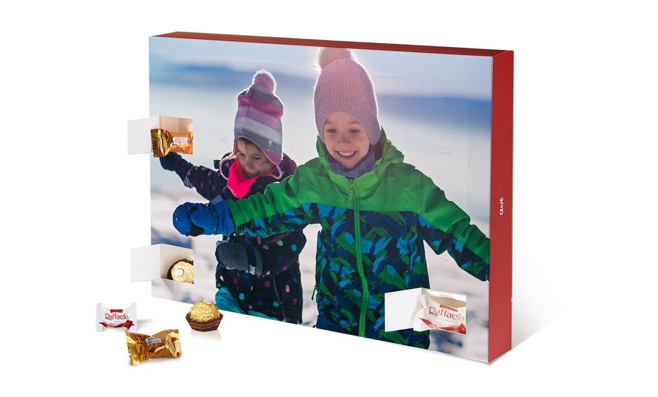 Dos niños felices abren un calendario de adviento en la nieve.