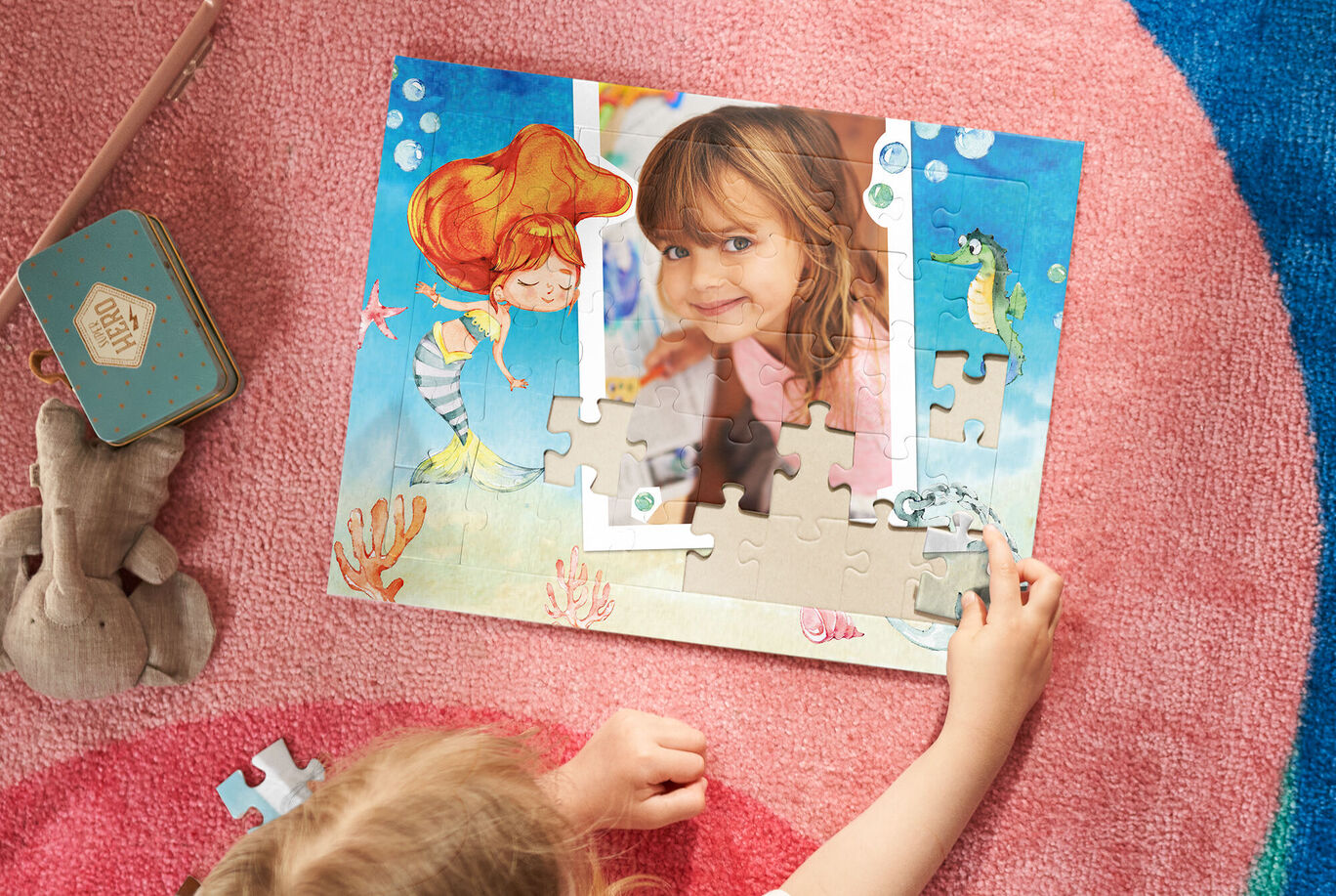 Un niño juega con un rompecabezas para crear una foto. El fondo es marino con un caballito de mar y peces.