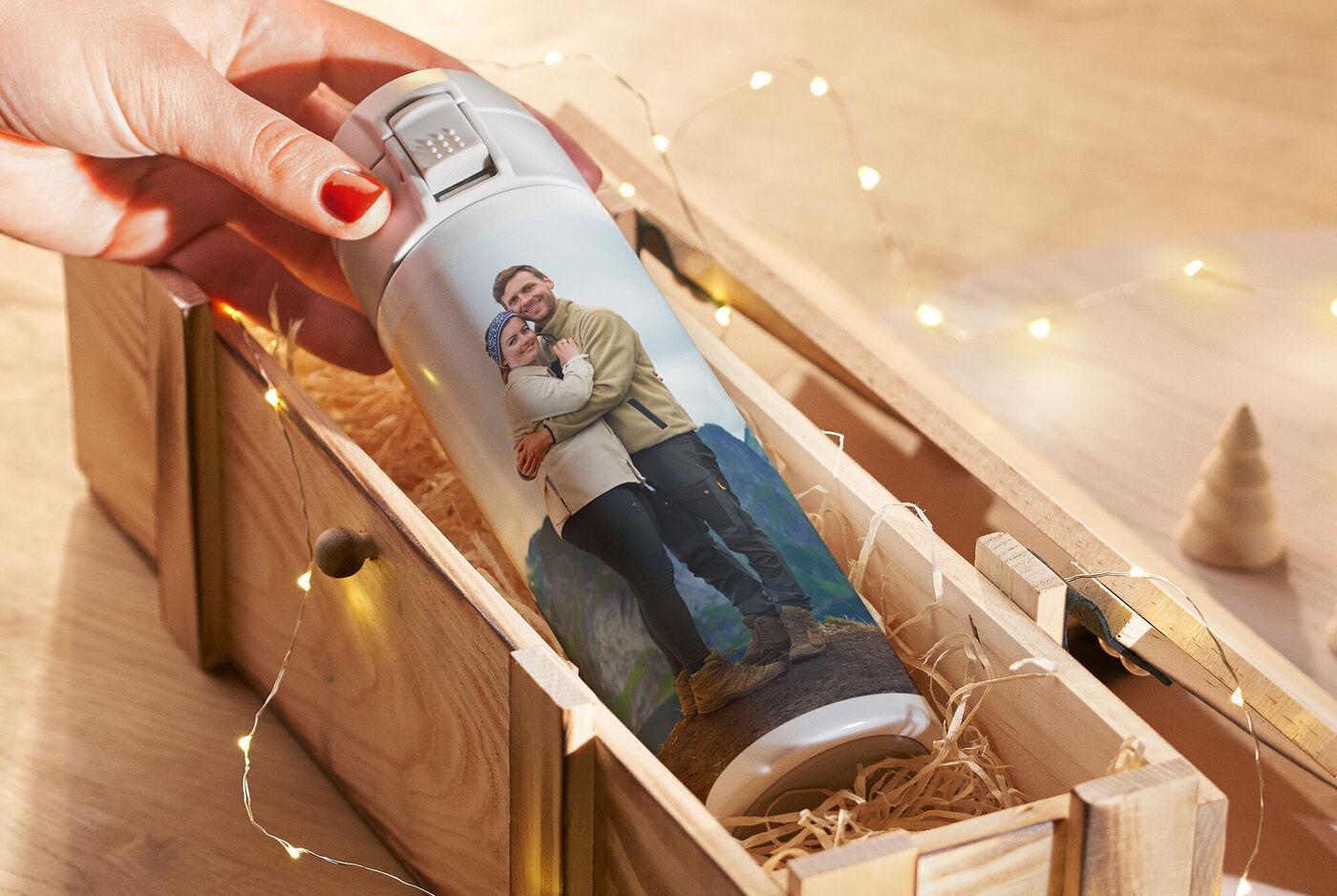 Una persona sostiene una botella térmica personalizada con una foto de una pareja. Es un regalo de Navidad.