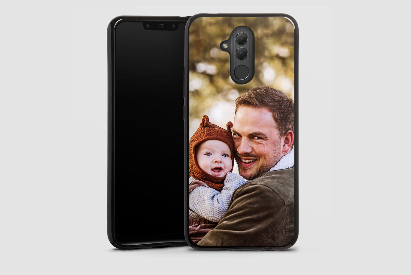 Un padre sostiene a su hijo en brazos con un smartphone al fondo.