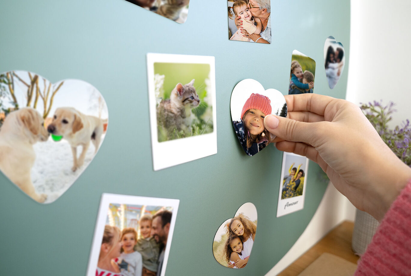 Una mano coloca una foto en forma de corazón en una pared con imágenes de momentos felices