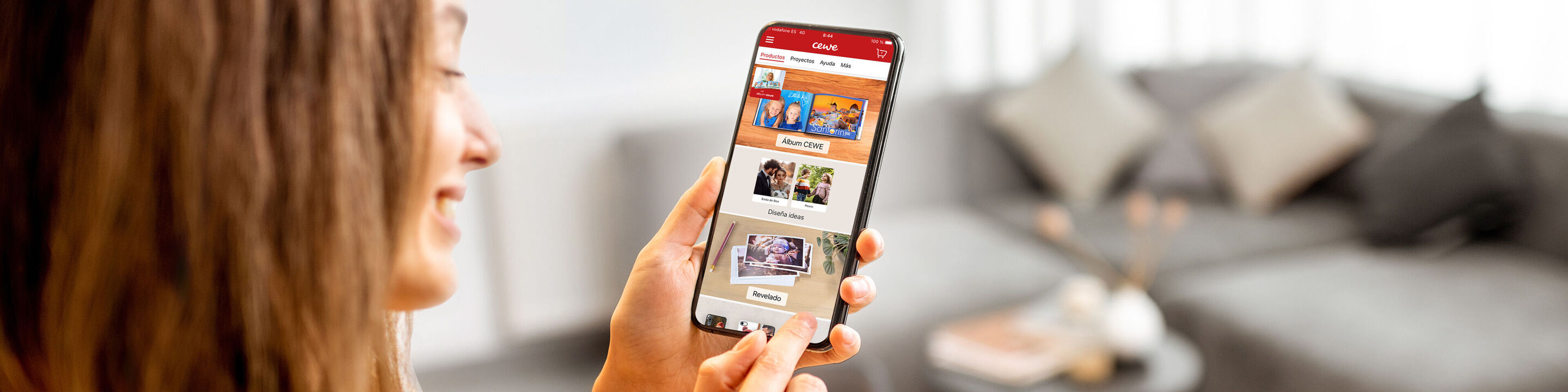 Joven usa la app CEWE Fotobuch en su smartphone para crear recuerdos.