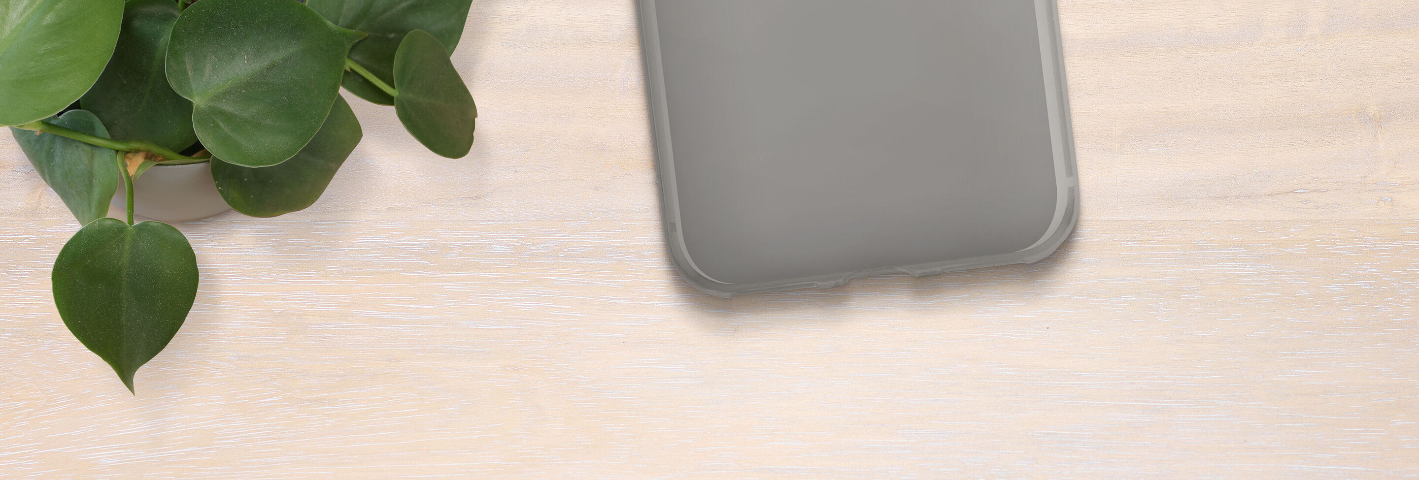 Funda de smartphone sobre una mesa con plantas verdes.