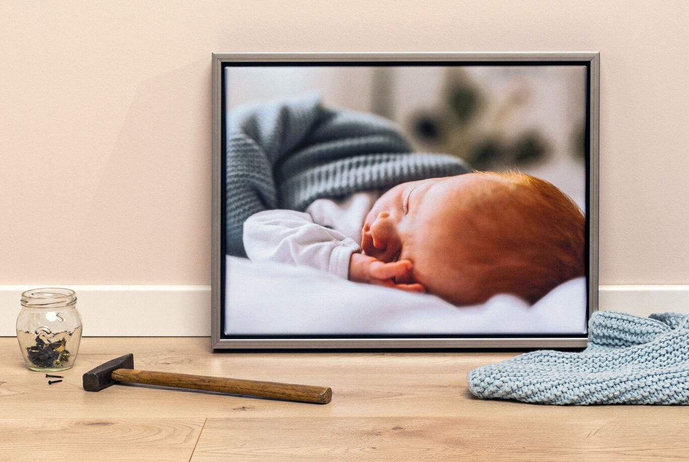 Un bebé dormido con cabello rojo en una manta gris.